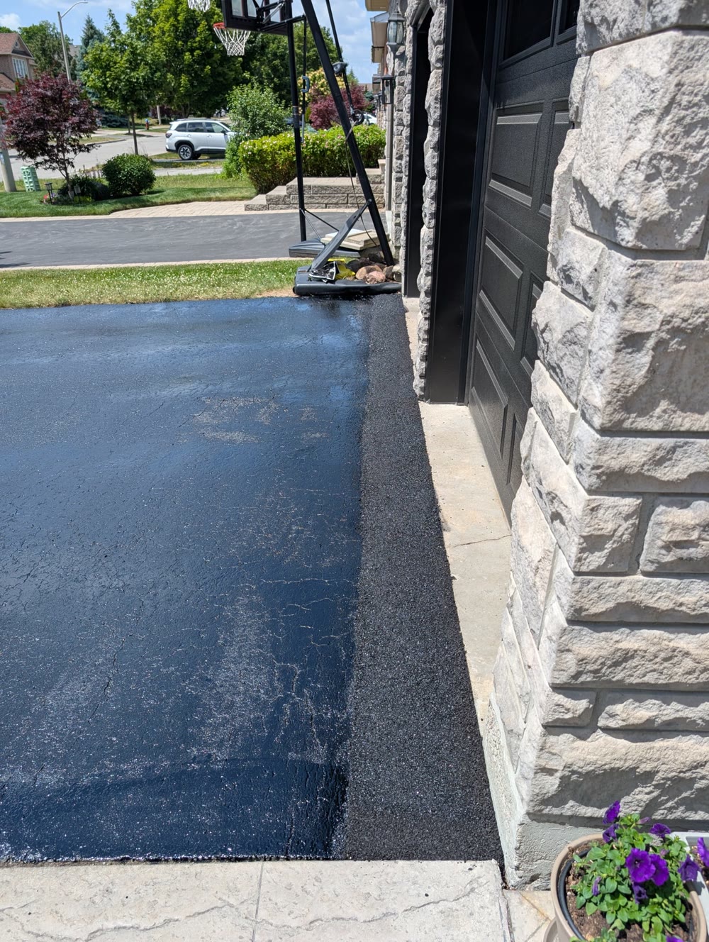 Sealcoating edge work beside a stone home